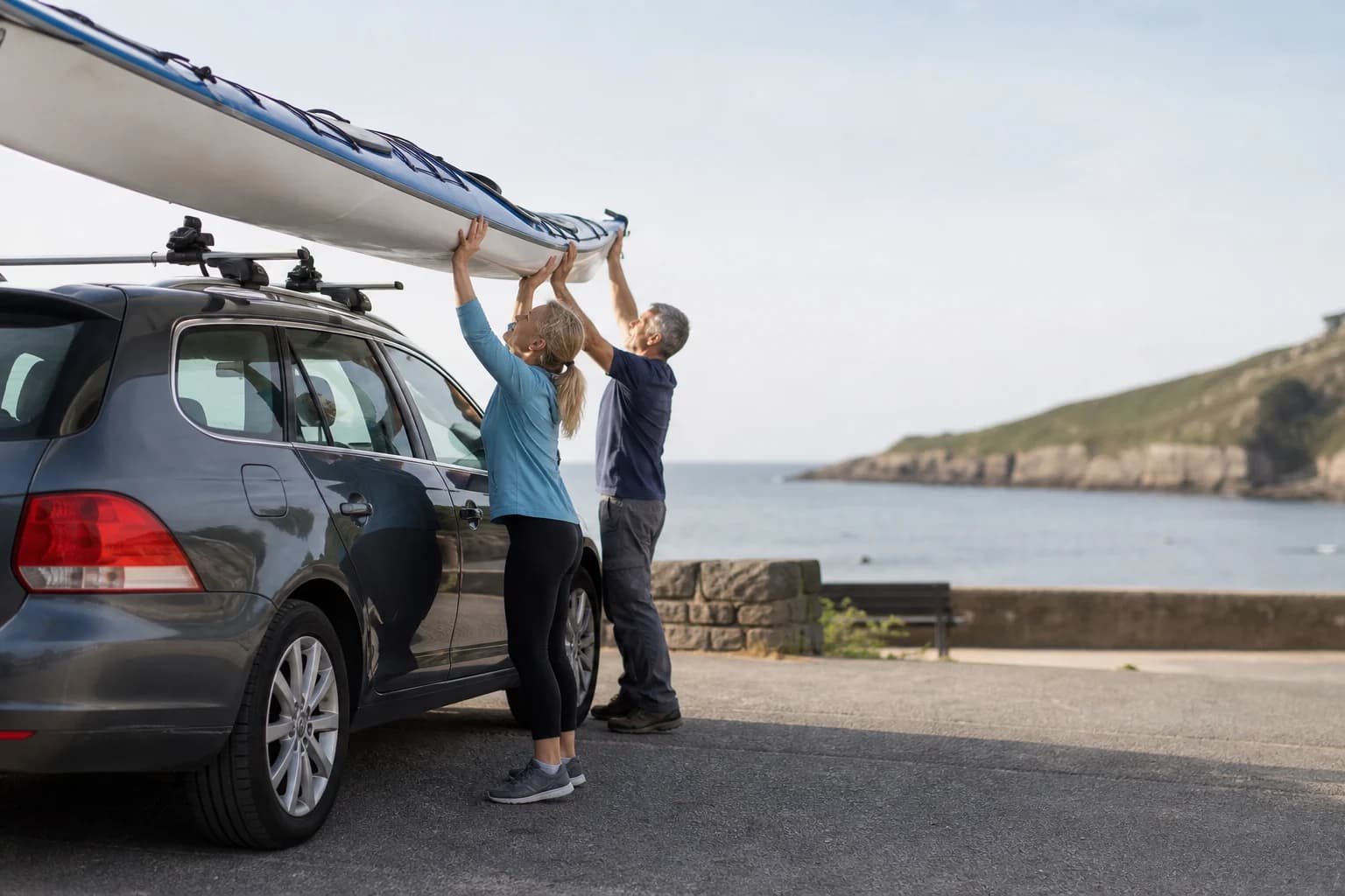 Couple lifting a kayak onto a roof rack using controlled overhead movement